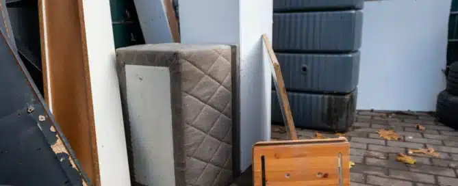 junk removal team carrying large furniture items like a couch and table from a home for proper disposal and hauling services